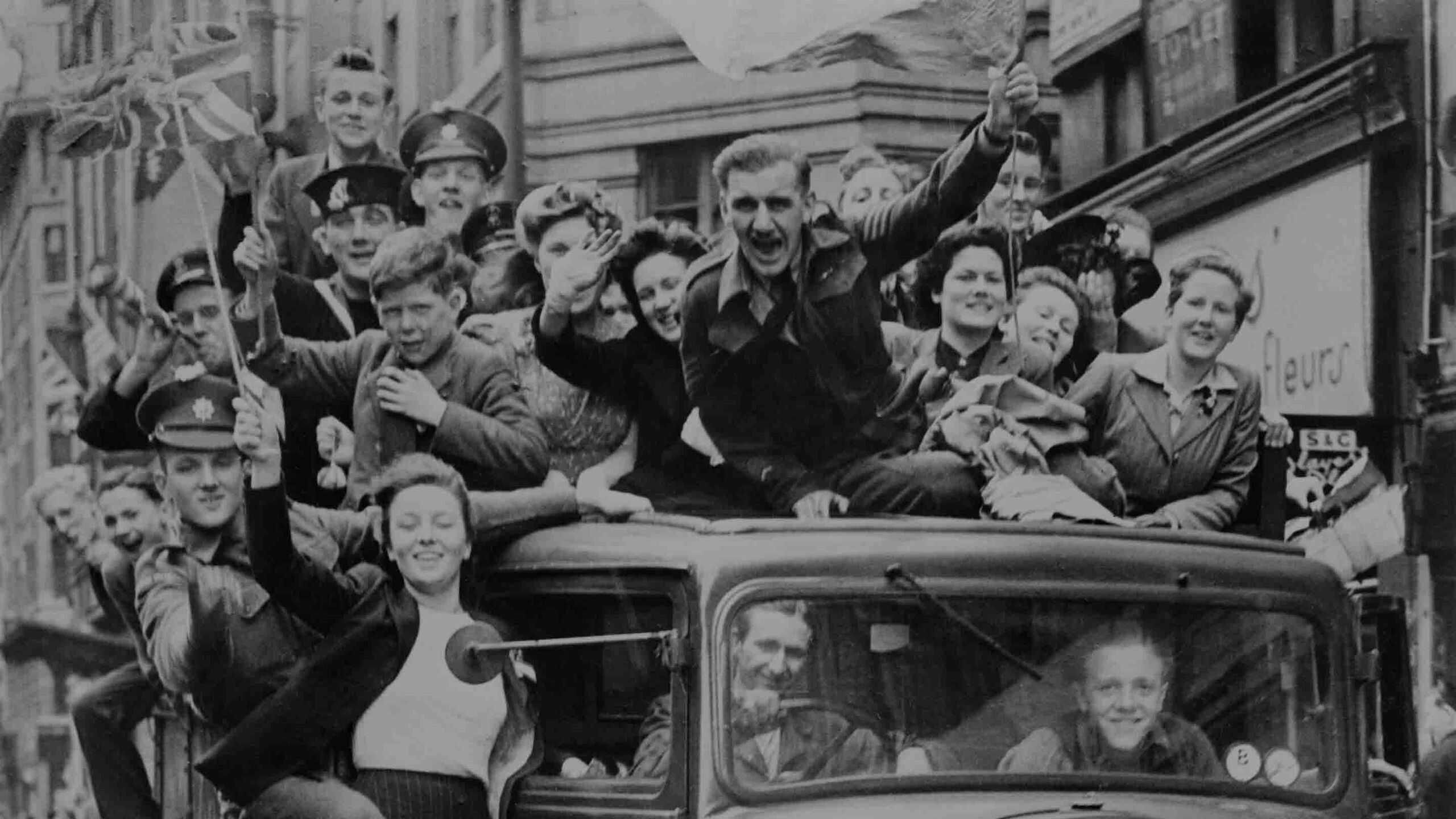 VE Day celebrations in London, 8 May 1945 – A truck full of revellers passes through the Strand as crowds mark the end of the war in Europe. Source: Imperial War Museum (Photograph HU 41808).