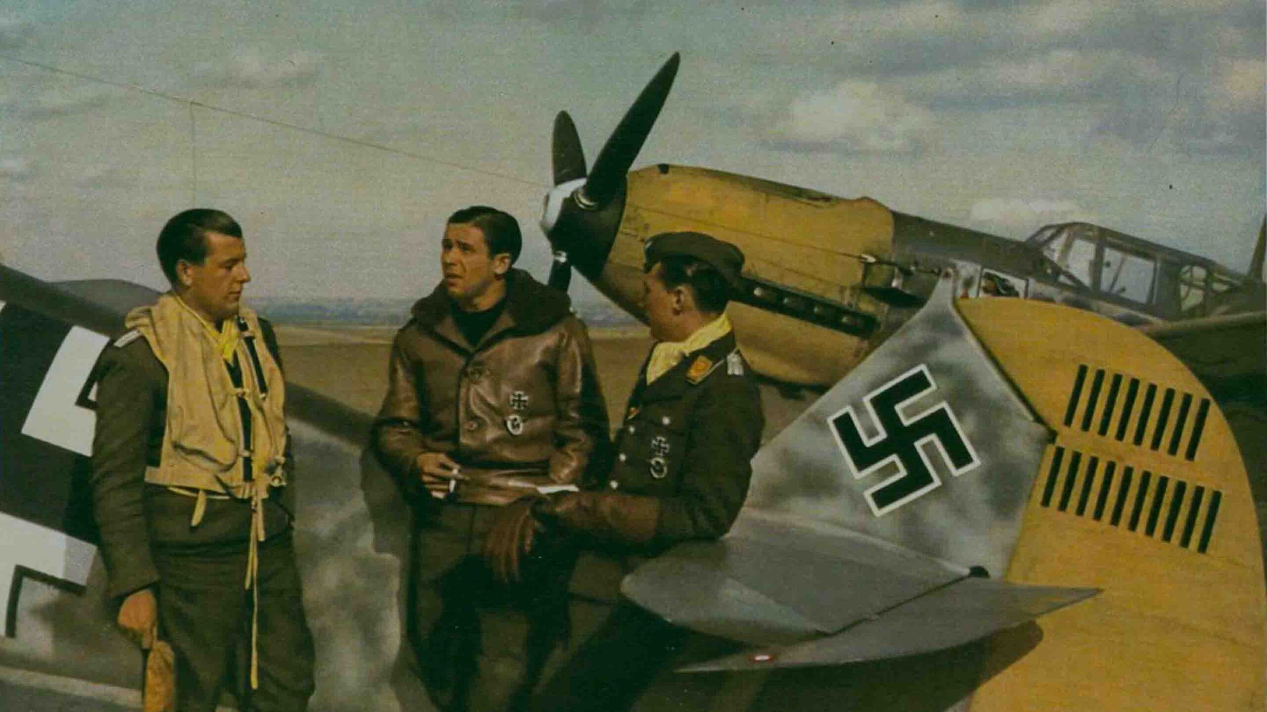 Luftwaffe fighter pilots converse between sorties, leaning on a Messerschmitt 109. Date and location unknown.